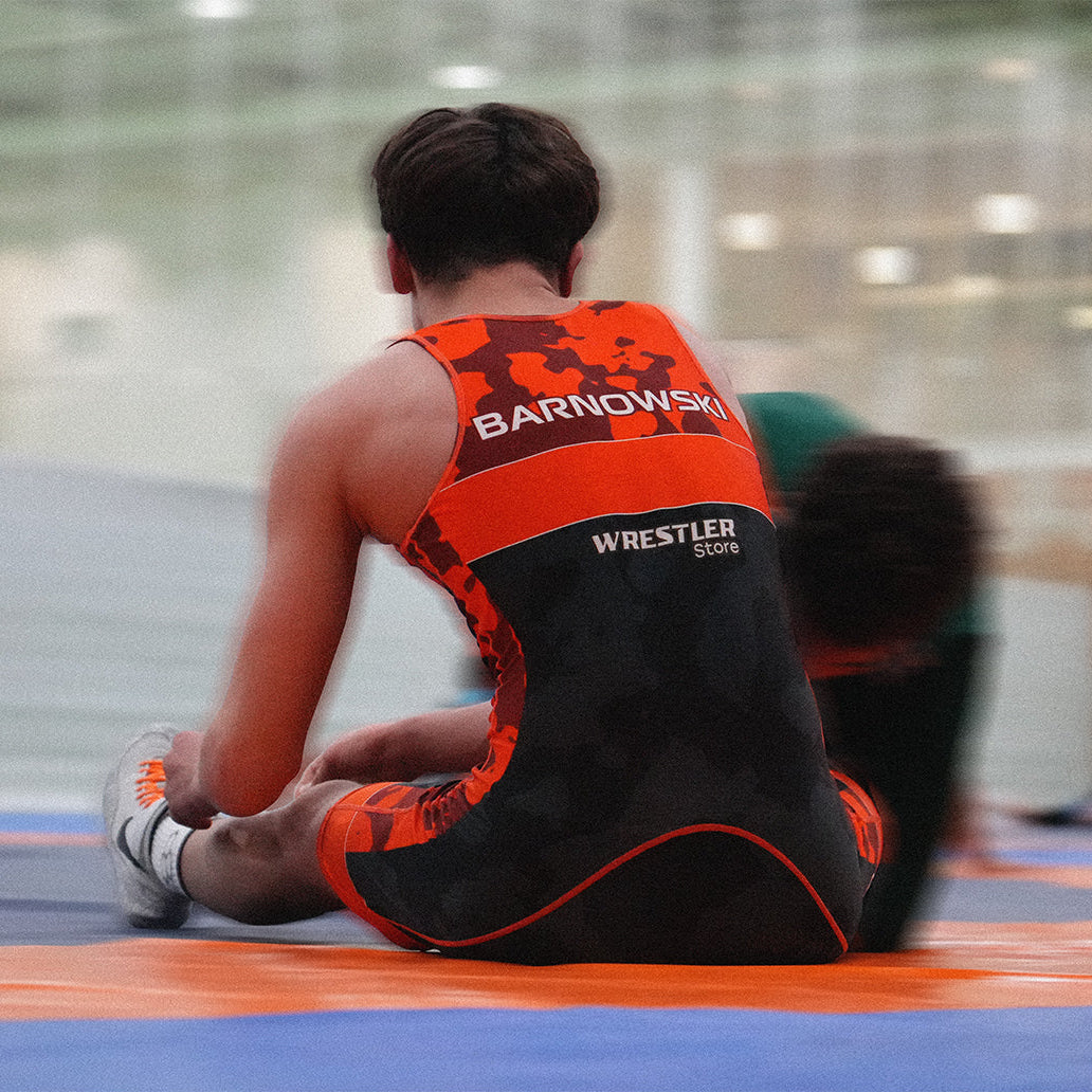 Ringer sitzt auf der Matte und trägt ein personalisiertes WrestlerStore Ringertrikot mit individuellem Namen auf dem Rücken