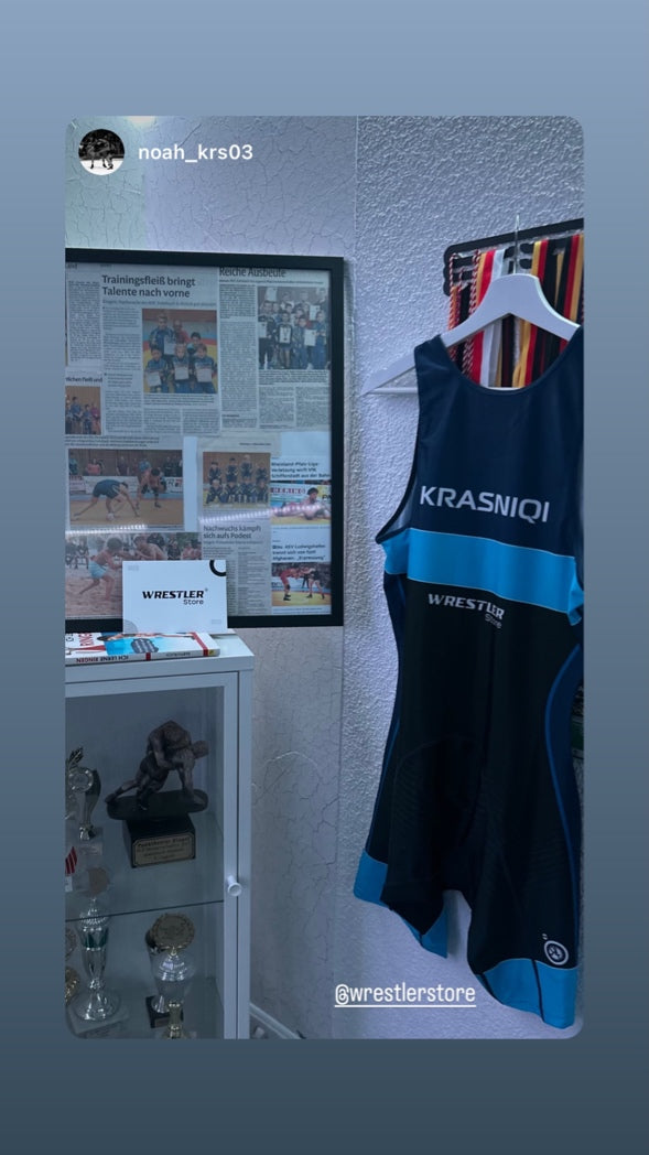 Personalisiertes Ringersinglet in Dunkelblau mit Namensaufdruck neben Ringer-Pokalen und Medaillen