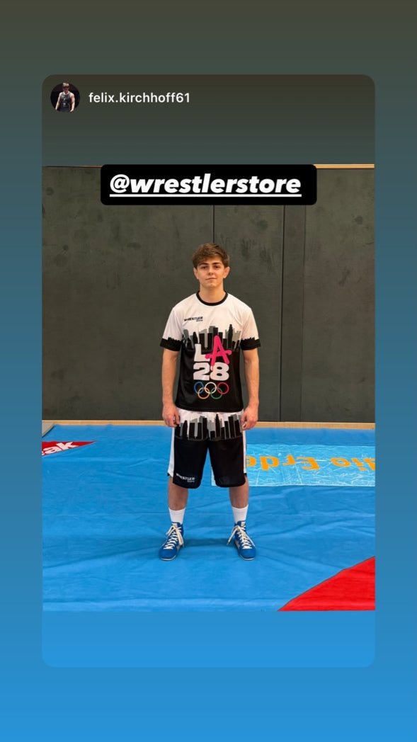 Junger Ringer trägt WrestlerStore LA28 T-Shirt und Shorts auf der Ringermatte im Training